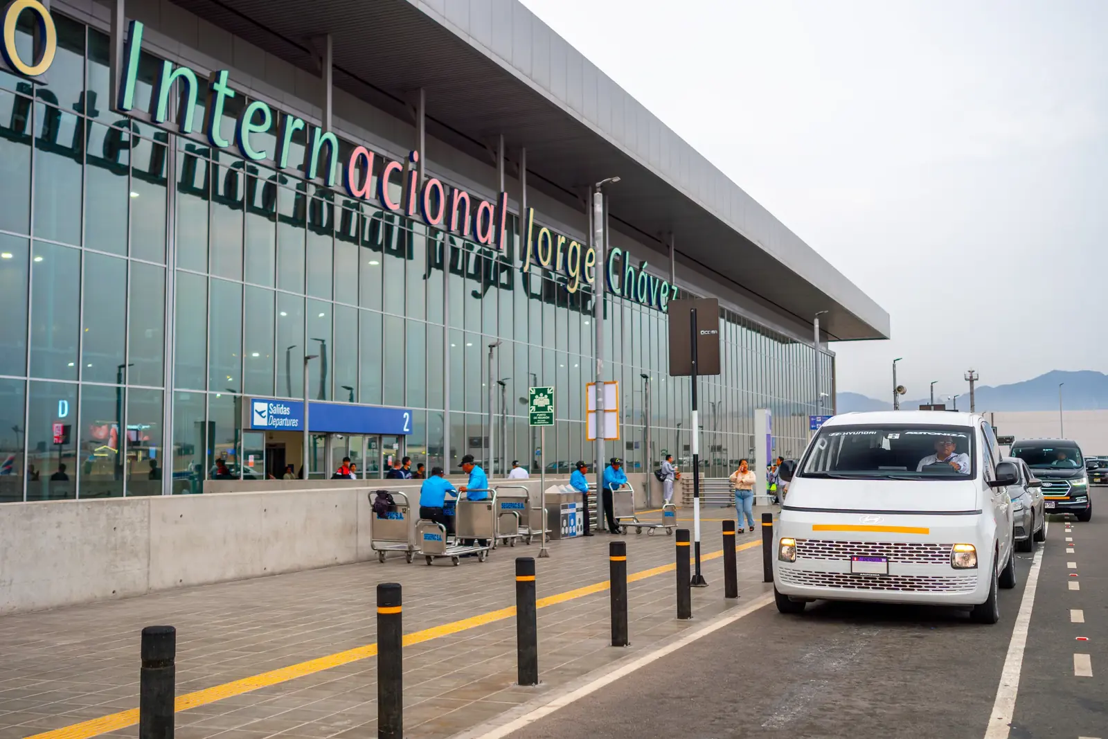 Fachada del Aeropuerto Internacional Jorge Chávez con una van Suisper en la zona de salidas