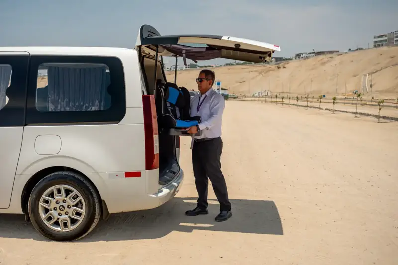Conductor acomodando un asiento para niños en una van Suisper