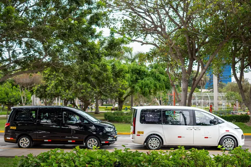 Dos vans Suisper estacionadas junto a un parque de Lima