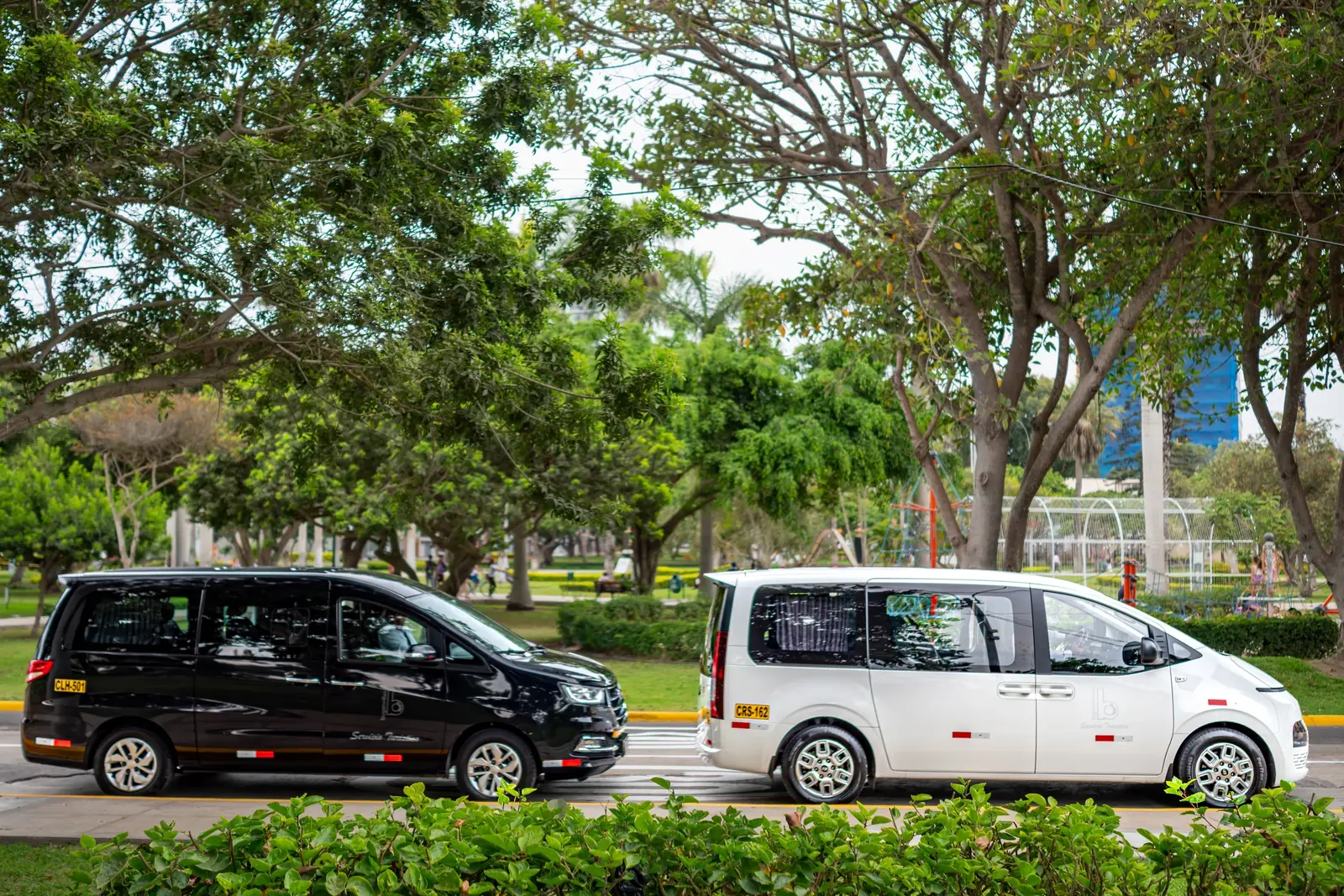 Dos vans Suisper estacionadas junto a un parque de Lima